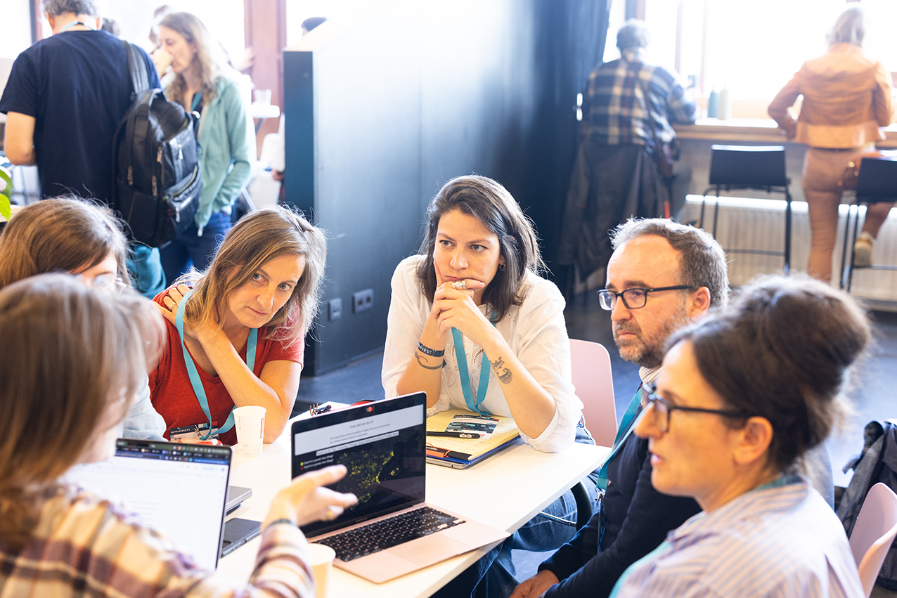 Six people wearing blue dataharvest lanyards, sitting around a table in deep discussion