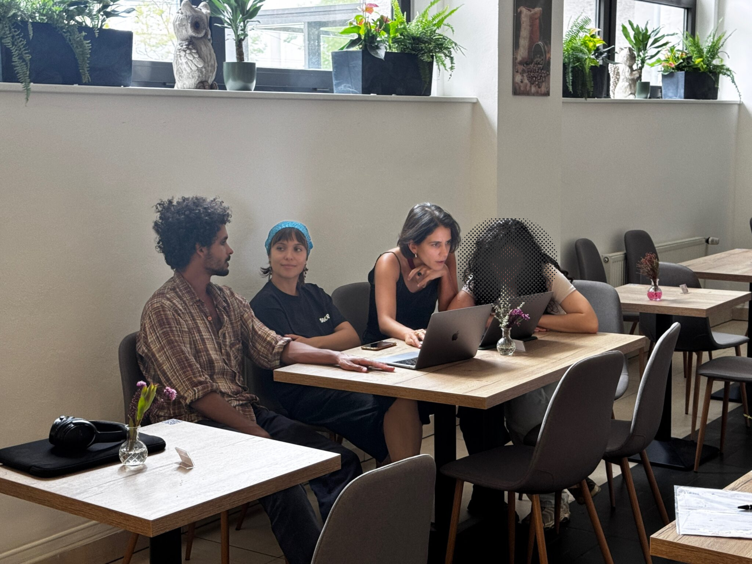 Four Climate Arena fellows working together on an investigation, two are in conversation, and two are huddled over a laptop screen. One person's face is pixellated, at their request.