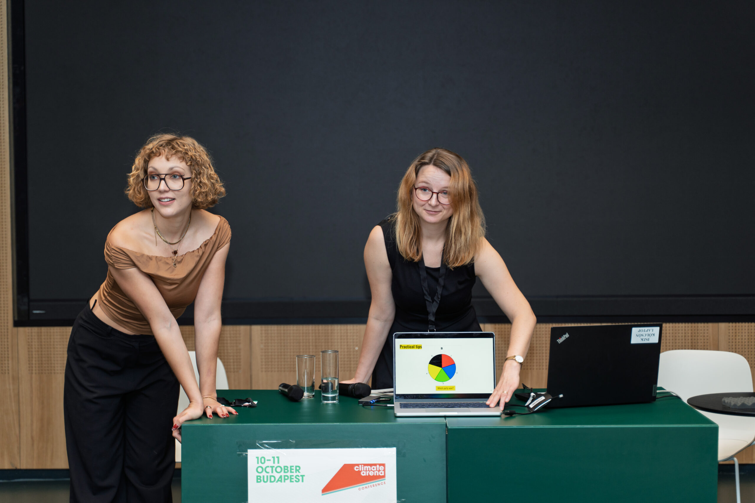 Two women, Ciara Cesaro-Tudic and Constanze Bayer, making a presentation, showing the audience a pie chart on a laptop screen.