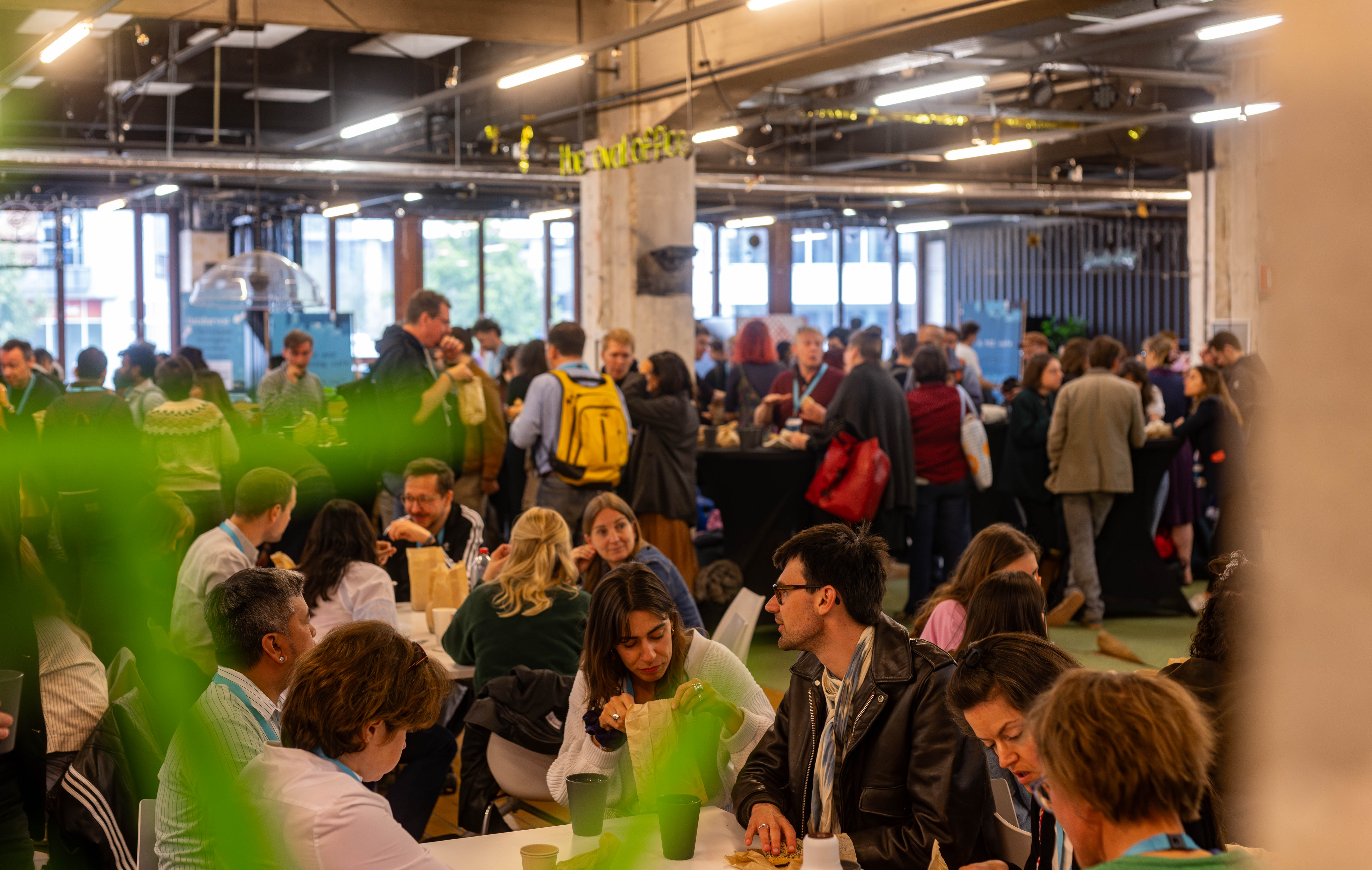 A large group of journalists in the networking room at Dataharvest 2025, all wearing blue lanyards.