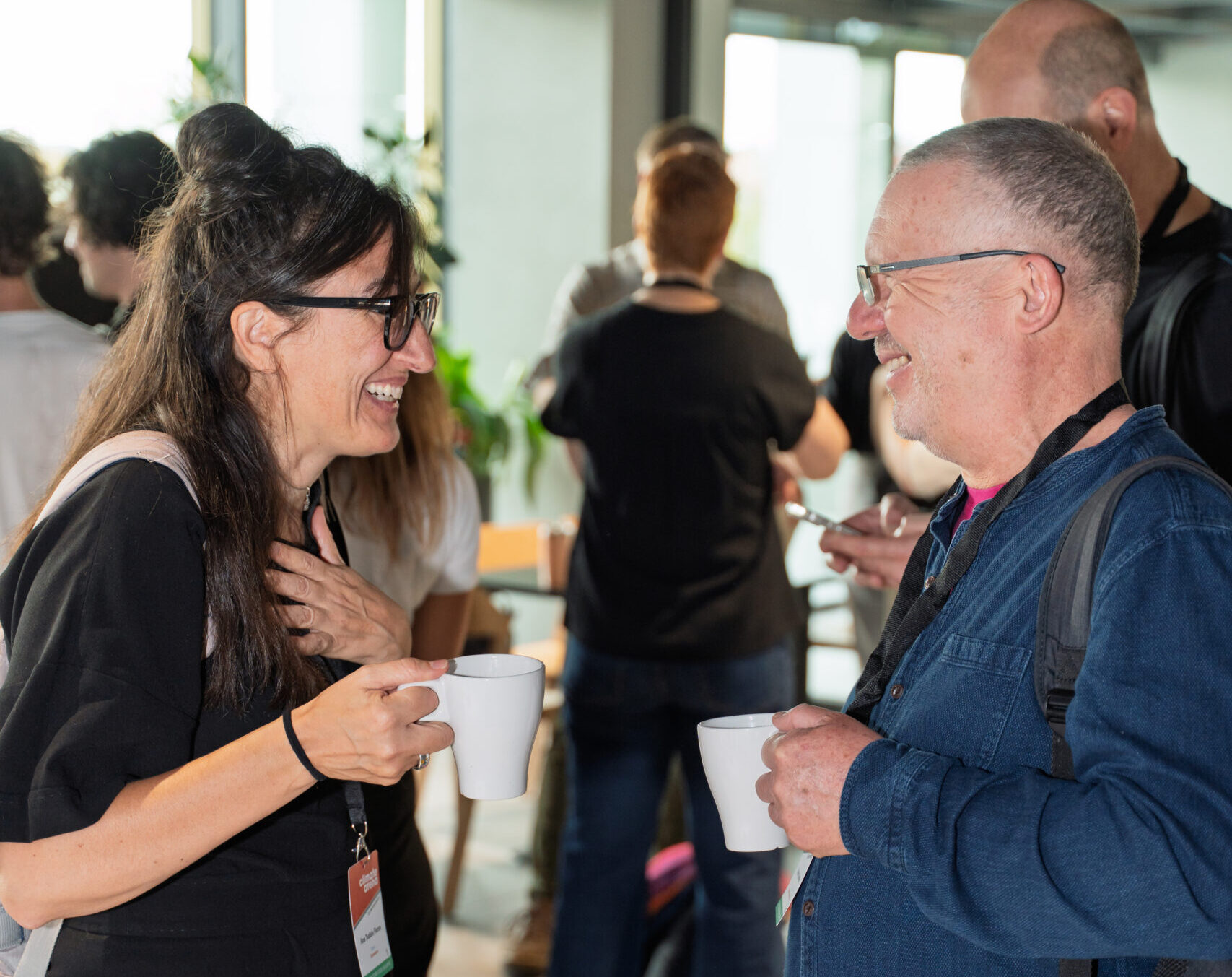 A woman and a man chat excitedly over coffee in a conference networking session.